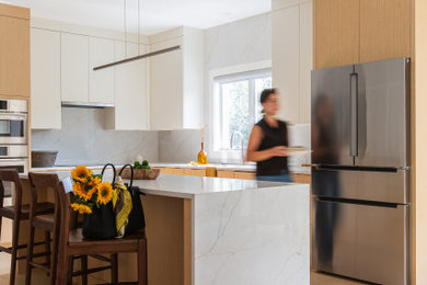 Inspiration for a mid-sized contemporary l-shaped light wood floor and beige floor eat-in kitchen remodel in Boston with flat-panel cabinets, light wood cabinets, quartz countertops, white backsplash, quartz backsplash, an island, white countertops, a drop-in sink and stainless steel appliances