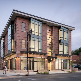 Создайте стильный интерьер: трехэтажный фасад многоквартирного дома в стиле модернизм с облицовкой из кирпича и плоской крышей - последний тренд