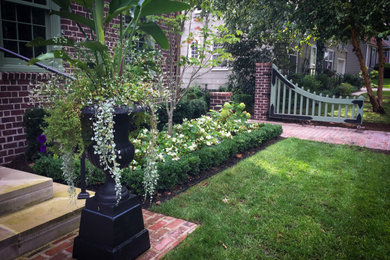This is an example of a mid-sized traditional shade front yard brick and wood fence landscaping in Kansas City for summer.