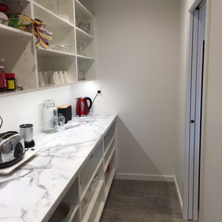 Mid-sized modern kitchen pantry appliance - Mid-sized minimalist galley vinyl floor kitchen pantry photo in Napier-Hastings with a double-bowl sink, white cabinets, laminate countertops and an island