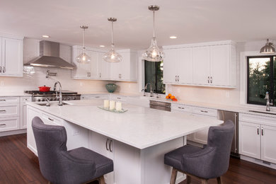 Inspiration for a large craftsman bamboo floor and brown floor kitchen remodel in Seattle with a farmhouse sink, shaker cabinets, white cabinets, quartz countertops, gray backsplash, porcelain backsplash, stainless steel appliances, an island and white countertops