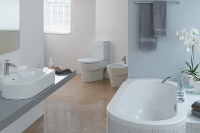 サリーにある中くらいなモダンスタイルのおしゃれなマスターバスルーム (ドロップイン型浴槽、一体型トイレ	、白い壁、テラコッタタイルの床、ベッセル式洗面器) の写真