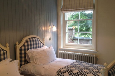 Modelo de habitación de invitados escandinava pequeña sin chimenea con paredes azules y moqueta