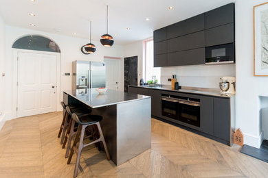 Matt black glass handleless kitchen with stainless steel worktop