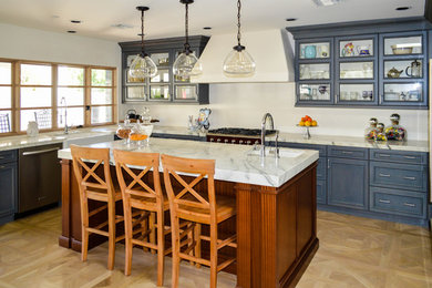 Design ideas for a large traditional u-shaped eat-in kitchen in Phoenix with a farmhouse sink, glass-front cabinets, blue cabinets, marble benchtops, stainless steel appliances, light hardwood floors and with island.