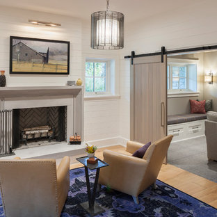 This is an example of a country look-out basement in Grand Rapids with white walls, light hardwood flooring and a standard fireplace.