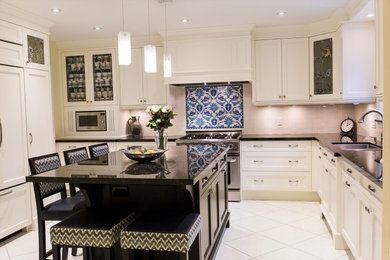 Inspiration for a mid-sized transitional u-shaped white floor and ceramic tile kitchen remodel in Toronto with an undermount sink, granite countertops, paneled appliances, an island, recessed-panel cabinets, white cabinets, white backsplash, subway tile backsplash and black countertops