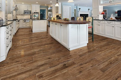 Huge elegant galley porcelain tile open concept kitchen photo in Raleigh with shaker cabinets, white cabinets, granite countertops, white backsplash, stainless steel appliances and two islands