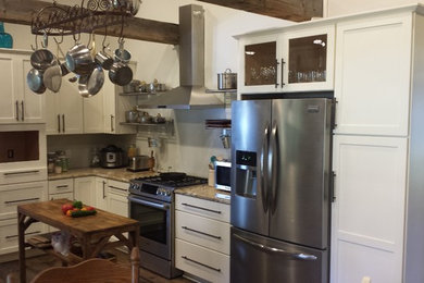 Example of a small transitional u-shaped dark wood floor and brown floor enclosed kitchen design in Other with shaker cabinets, white cabinets, granite countertops, stainless steel appliances and an island