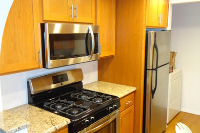 Kitchen pantry - small transitional galley vinyl floor and brown floor kitchen pantry idea in Oklahoma City with a double-bowl sink, shaker cabinets, medium tone wood cabinets, granite countertops, white backsplash, ceramic backsplash, stainless steel appliances and no island