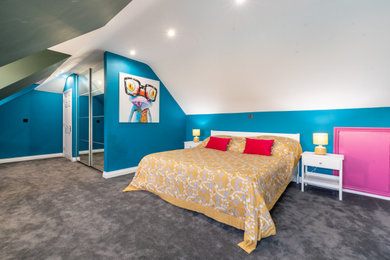 Photo of a large contemporary master and grey and yellow loft bedroom in Kent with blue walls, carpet and grey floors.