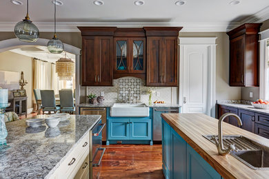 Photo of a traditional kitchen in Huntington with a farmhouse sink, shaker cabinets, dark wood cabinets, stainless steel appliances, medium hardwood floors and multiple islands.