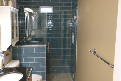Large trendy 3/4 blue tile and ceramic tile laminate floor, beige floor and double-sink alcove shower photo in Columbus with raised-panel cabinets, light wood cabinets, a two-piece toilet, beige walls, an undermount sink, granite countertops, a hinged shower door, black countertops and a freestanding vanity