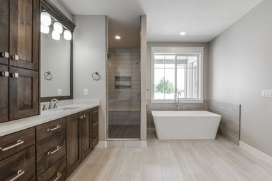 Inspiration for a large arts and crafts master bathroom in Salt Lake City with recessed-panel cabinets, brown cabinets, a freestanding tub, an alcove shower, gray tile, grey walls, an undermount sink, grey floor and a hinged shower door.