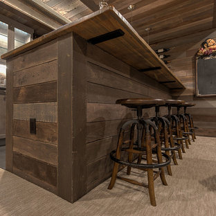 Photo of a large rustic fully buried basement in Other with brown walls, carpet, a hanging fireplace, a tiled fireplace surround and beige floors.