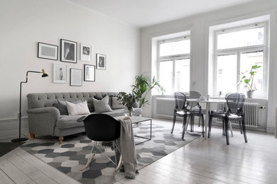 Large transitional enclosed living room in Stockholm with white walls and light hardwood floors.