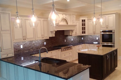 Kitchen - mid-sized transitional u-shaped ceramic tile kitchen idea in New York with an undermount sink, raised-panel cabinets, white cabinets, granite countertops, black backsplash, matchstick tile backsplash, stainless steel appliances and an island