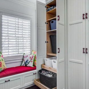 ダラスのカントリー風おしゃれなランドリールーム (落し込みパネル扉のキャビネット、白いキャビネット、無垢フローリング、赤いキッチンカウンター) の写真