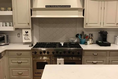 Example of a mid-sized arts and crafts l-shaped medium tone wood floor and brown floor kitchen design in New York with raised-panel cabinets, white cabinets, quartz countertops, stainless steel appliances, an island and white countertops