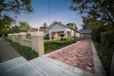 This is an example of an expansive contemporary front yard driveway in Sydney with a garden path and natural stone pavers.