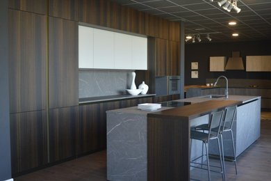 Foto di una cucina minimalista di medie dimensioni con lavello sottopiano, ante lisce, ante in legno bruno, top in laminato, paraspruzzi grigio, parquet scuro, pavimento marrone e top grigio