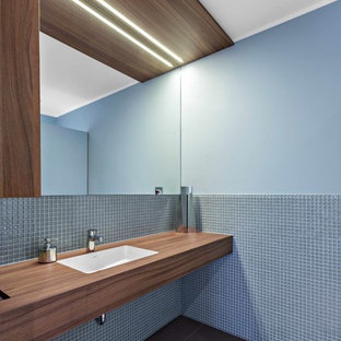 Foto di una stanza da bagno moderna con piastrelle blu, piastrelle a mosaico, pareti blu, lavabo sottopiano, top in legno e top marrone