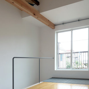 Esempio di una piccola camera matrimoniale etnica con pareti bianche, pavimento in legno verniciato e pavimento marrone