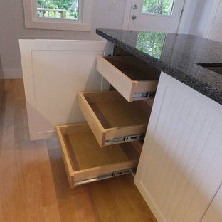 Beach style kitchen pantry pictures - Inspiration for a beach style galley light wood floor kitchen pantry remodel in Orlando with an undermount sink, beaded inset cabinets, white cabinets, granite countertops, glass tile backsplash, stainless steel appliances and an island