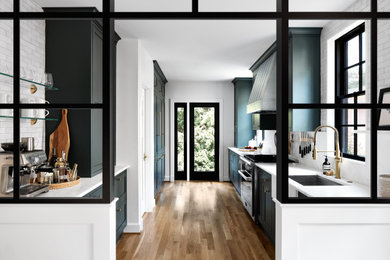 Mid-sized transitional galley light wood floor and brown floor eat-in kitchen photo in DC Metro with flat-panel cabinets, green cabinets, marble countertops, white backsplash, ceramic backsplash, black appliances and white countertops