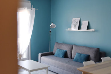 Inspiration pour un salon design avec un mur bleu, sol en stratifié, aucune cheminée et un sol gris.