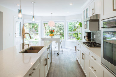 Design ideas for a large scandinavian l-shaped eat-in kitchen in Vancouver with an undermount sink, shaker cabinets, white cabinets, quartz benchtops, grey splashback, glass tile splashback, stainless steel appliances, vinyl floors, multiple islands, grey floor and white benchtop.