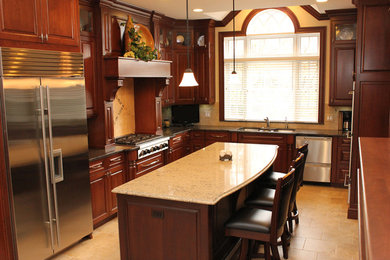 Kitchen - large traditional u-shaped porcelain tile kitchen idea in Cleveland with raised-panel cabinets, brown cabinets, quartz countertops, beige backsplash, porcelain backsplash, stainless steel appliances and an island