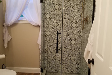 Corner shower - transitional cement tile vinyl floor and brown floor corner shower idea in Philadelphia with a hinged shower door