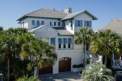 Example of a large island style white three-story stucco exterior home design in Miami with a hip roof