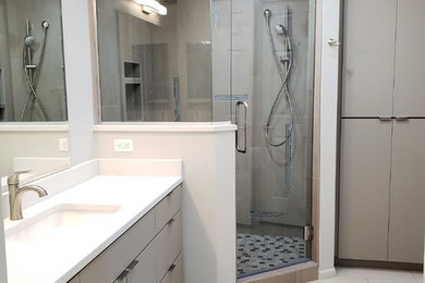 Mid-sized trendy master multicolored tile and glass sheet vinyl floor corner shower photo in Phoenix with flat-panel cabinets, gray cabinets, an undermount sink, quartzite countertops, a hinged shower door and white countertops