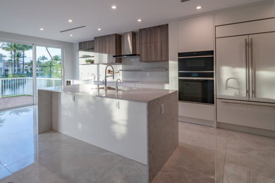 Large trendy single-wall porcelain tile and gray floor eat-in kitchen photo in Miami with an integrated sink, flat-panel cabinets, white cabinets, quartz countertops, gray backsplash, quartz backsplash, paneled appliances, an island and gray countertops
