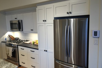Eat-in kitchen - mid-sized transitional single-wall dark wood floor and brown floor eat-in kitchen idea in Montreal with shaker cabinets, white cabinets, quartz countertops, stainless steel appliances and an island