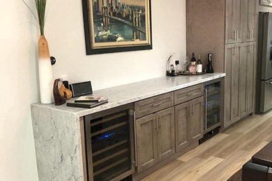Photo of a mid-sized contemporary single-wall home bar in Phoenix with shaker cabinets, medium wood cabinets, quartzite benchtops, light hardwood floors, brown floor and multi-coloured benchtop.