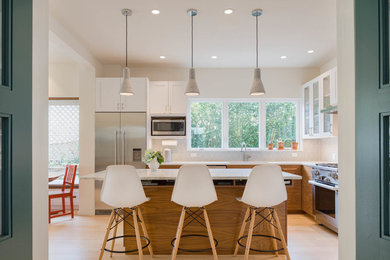 Design ideas for a mid-sized transitional l-shaped eat-in kitchen in Seattle with an undermount sink, glass-front cabinets, quartz benchtops, grey splashback, ceramic splashback, stainless steel appliances, light hardwood floors, with island, white benchtop, medium wood cabinets and beige floor.