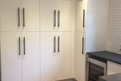 Mid-sized transitional u-shaped concrete floor and gray floor utility room photo in Other with an undermount sink, flat-panel cabinets, white cabinets, a side-by-side washer/dryer and black countertops