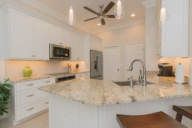 Example of a mid-sized transitional galley porcelain tile and beige floor enclosed kitchen design in Miami with a double-bowl sink, flat-panel cabinets, white cabinets, granite countertops, white backsplash, ceramic backsplash and stainless steel appliances
