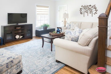 Inspiration for a mid-sized timeless enclosed light wood floor and brown floor living room remodel in Milwaukee with white walls, no fireplace and a tv stand