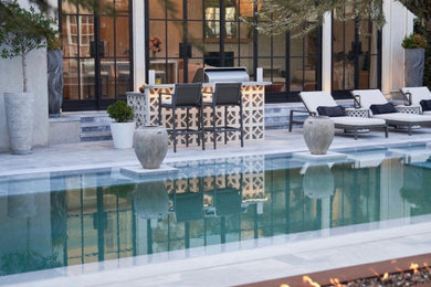 Diseño de casa de la piscina y piscina infinita actual rectangular en patio trasero con adoquines de piedra natural
