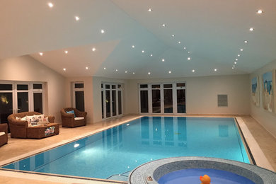 Medium sized contemporary back rectangular above ground swimming pool in Essex with a pool house and tiled flooring.
