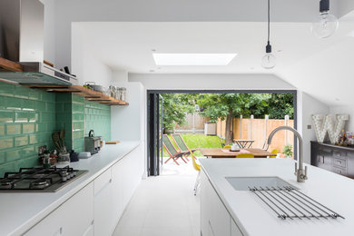 Design ideas for a large contemporary kitchen in London with a submerged sink, white cabinets, composite countertops, green splashback, ceramic splashback, stainless steel appliances, porcelain flooring, an island, grey floors and white worktops.