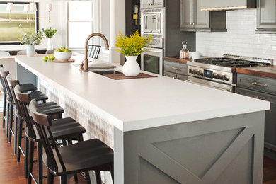 Inspiration for a mid-sized transitional single-wall eat-in kitchen in New York with an undermount sink, raised-panel cabinets, grey cabinets, concrete benchtops, white splashback, subway tile splashback, stainless steel appliances, medium hardwood floors, with island, brown floor and multi-coloured benchtop.