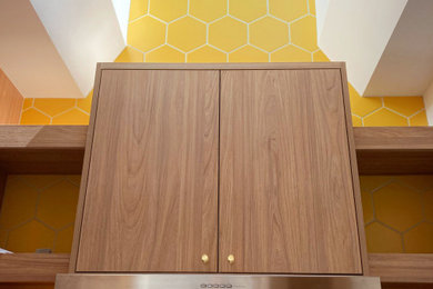 Photo of a modern kitchen in San Francisco with an undermount sink, recessed-panel cabinets, light wood cabinets, yellow splashback, ceramic splashback, stainless steel appliances, light hardwood floors, with island and grey benchtop.