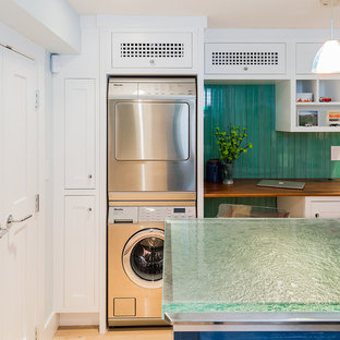 Inspiration for a medium sized traditional separated utility room in Boston with white cabinets, glass worktops, green walls, light hardwood flooring, a stacked washer and dryer, shaker cabinets and turquoise worktops.