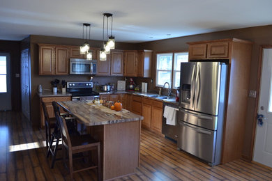 Inspiration for a mid-sized cottage l-shaped open concept kitchen remodel in Indianapolis with a drop-in sink, raised-panel cabinets, medium tone wood cabinets, laminate countertops, stainless steel appliances and an island