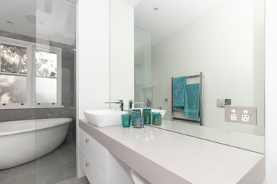 Mid-sized modern 3/4 bathroom in Sydney with flat-panel cabinets, white cabinets, a freestanding tub, an open shower, a one-piece toilet, multi-coloured tile, porcelain tile, multi-coloured walls, porcelain floors, a vessel sink, engineered quartz benchtops, grey floor, an open shower and grey benchtops.